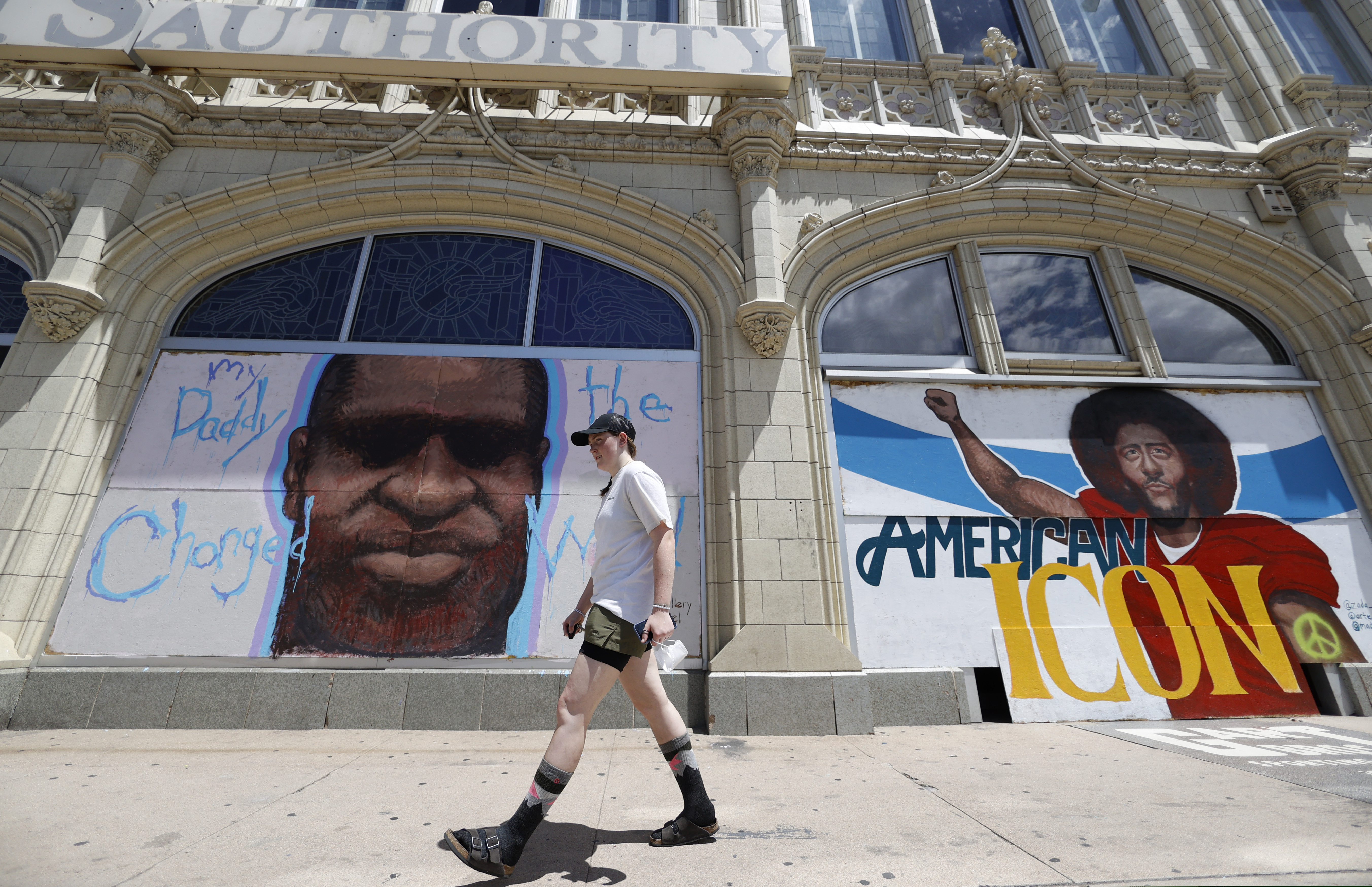 A pedestrian passing murals to honor George Floyd and former NFL quarterback Colin Kaepernick covering pieces of plywood used to shield windows in an empty storefront south of the State Capitol in Denver, Colo., last June.