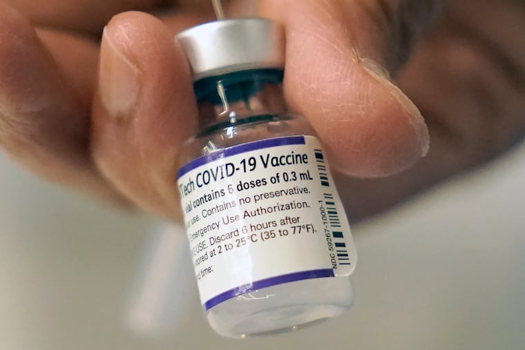 A doctor loads a dose of Pfizer COVID-19 vaccine into a syringe at a mobile vaccination clinic in Worcester, Mass.