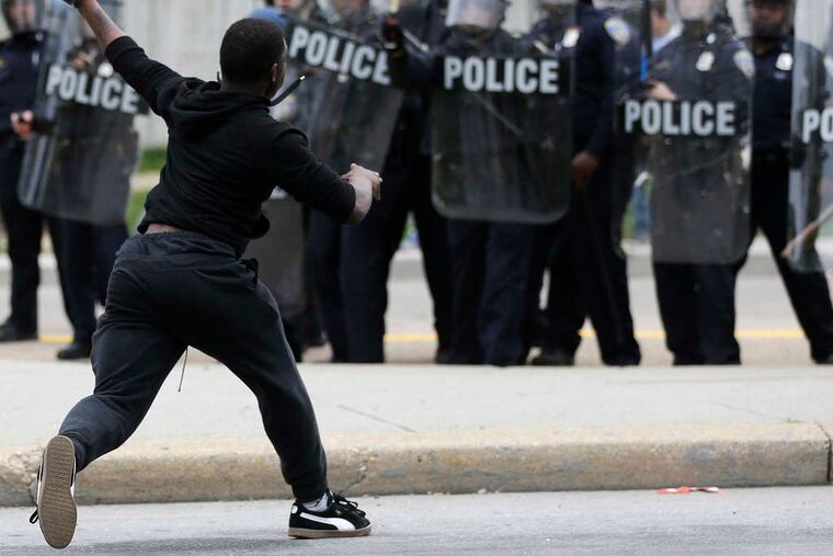 PATRICK SEMANSKY / ASSOCIATED PRESS A protester in Baltimore confronts police in riot gear during a tumultuous day.