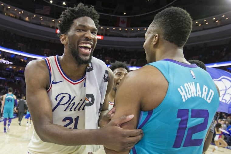 Joel Embiid, left, sharing a light moment with Charlotte’s Dwight Howard, is keeping close tabs on the playoff race.