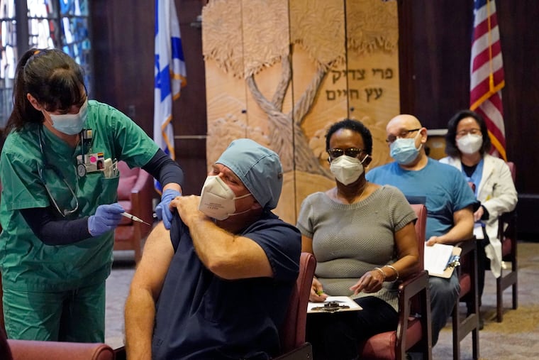 In this Dec. 30 photo, nurse manager Rob Treiber receives a COVID-19 vaccine at Hebrew Rehabilitation Center in Boston.