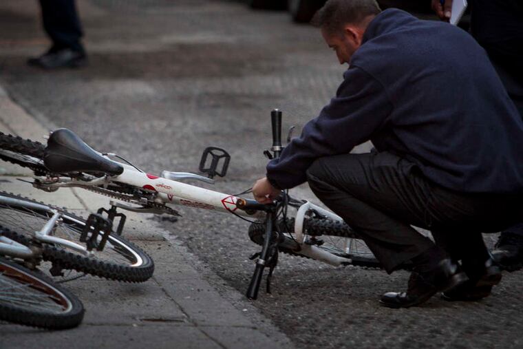 A detective examines a bicycle allegedly belonging to a man who killed a man early Thursday on Watkins Street.