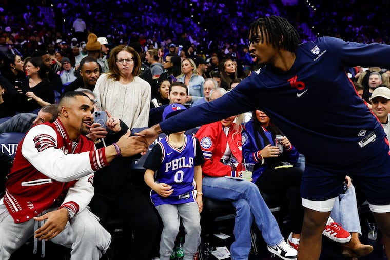 Sixers guard Tyrese Maxey greets Eagles quarterback Jalen Hurts during a break from Monday's game.