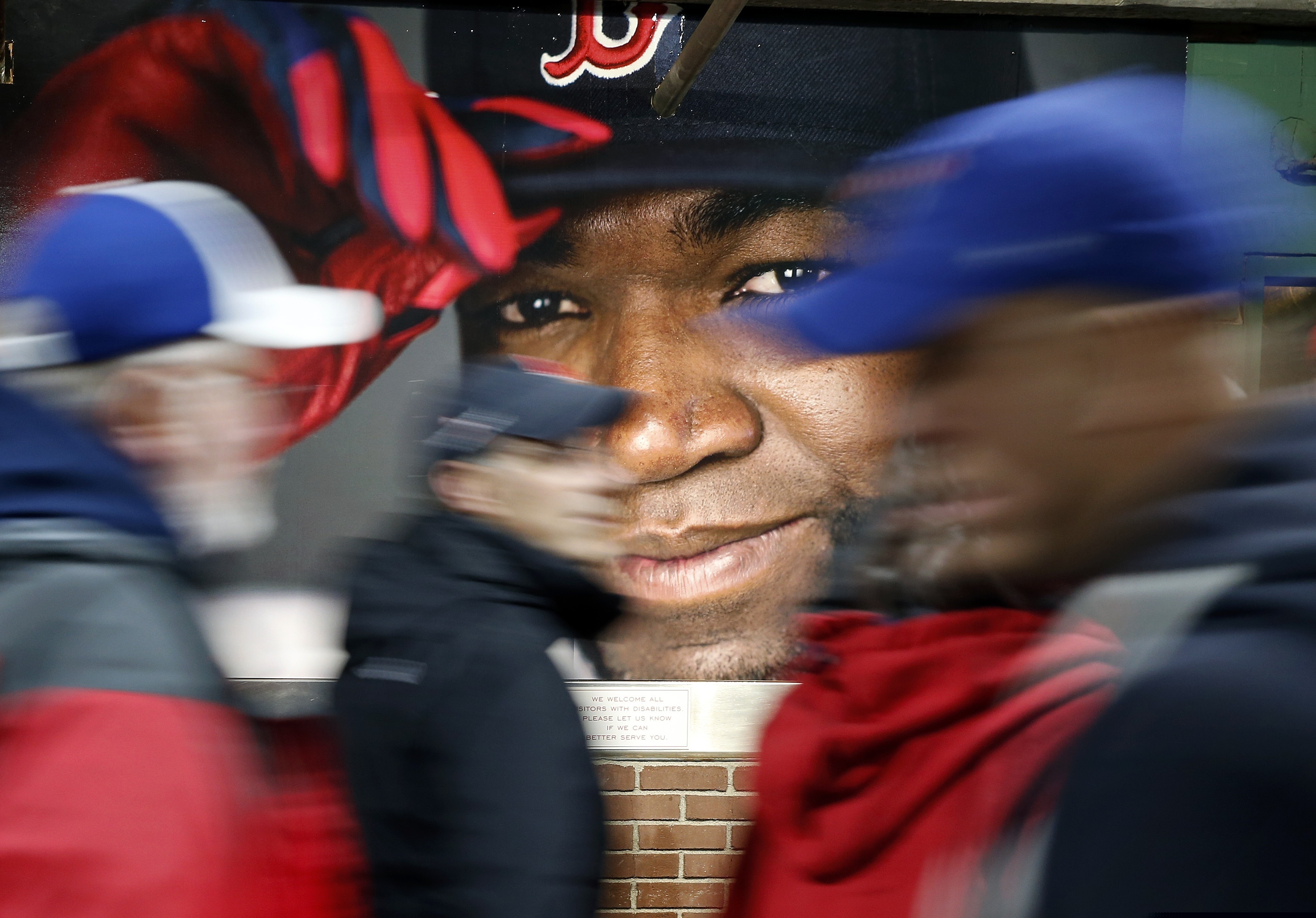 Fanáticos pasan frente a una fotografía de David Ortiz, de los Medias Rojas de Boston, antes de un partido de béisbol contra los Azulejos de Toronto en el Fenway Park en Boston.