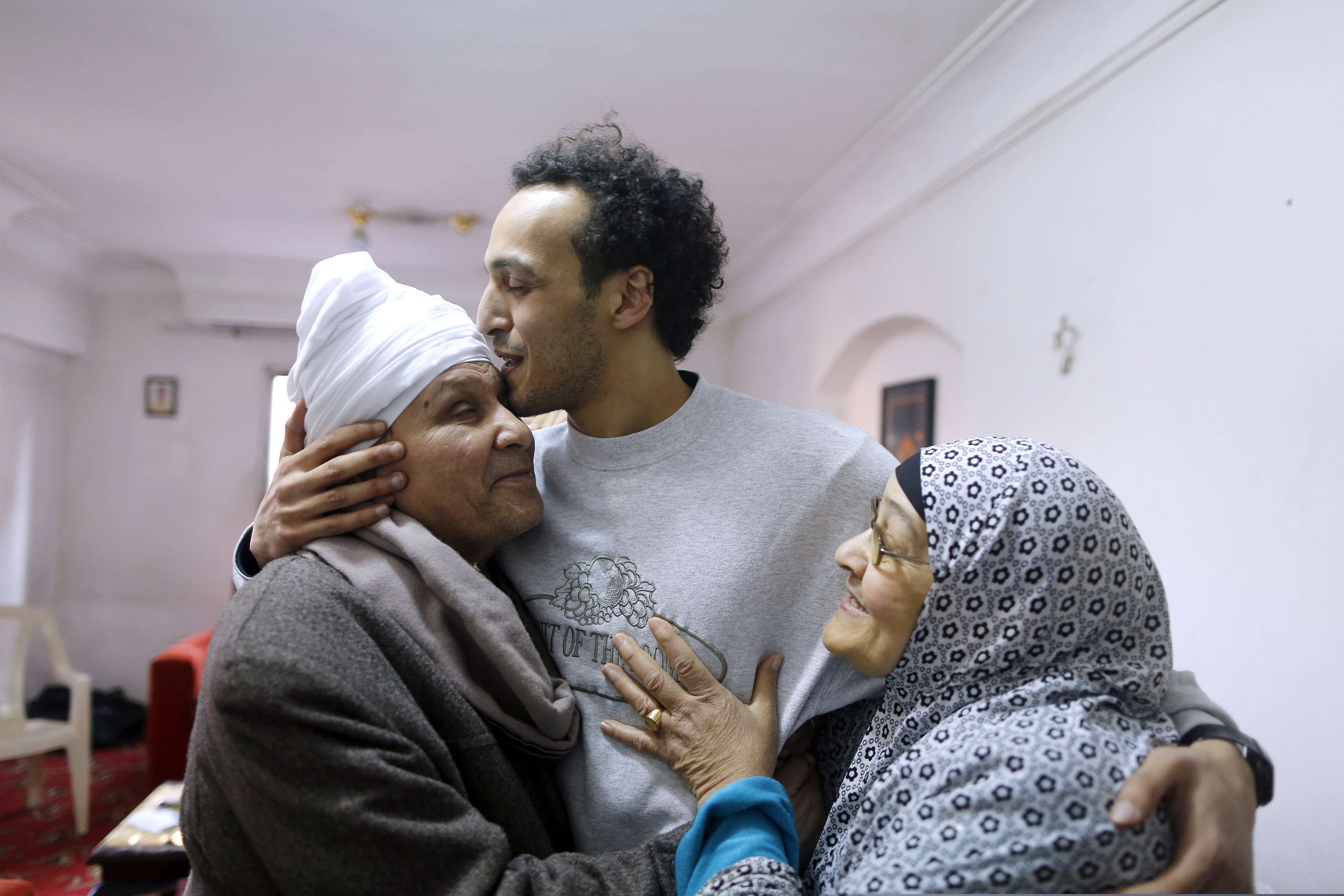 Mahmoud Abu Zaid, a photojournalist known as Shawkan, center, is hugged by his parents at his home in Cairo, Egypt, Monday, March 4, 2019. Shawkan was released after after five years in prison. (AP Photo/Amr Nabil)