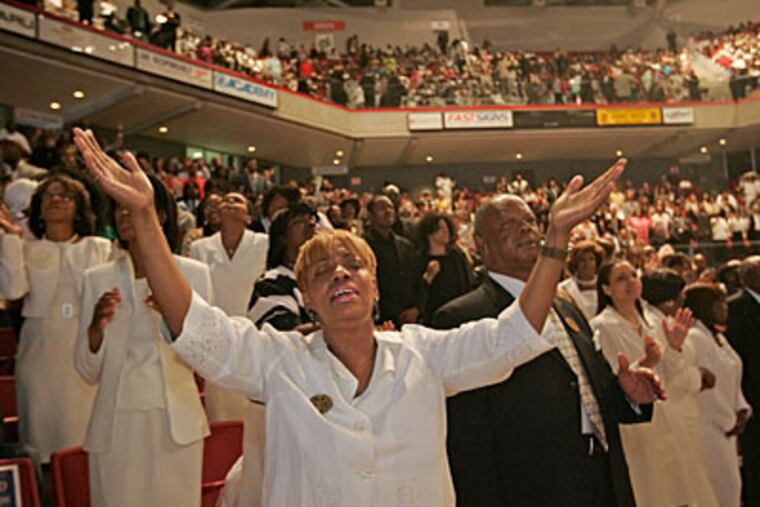 Denise Bryant, a Deconaide with Enon Baptist Church, holds up her hands druing the singing of a hymn during Easter services. ( Michael Bryant / Staff Photographer )