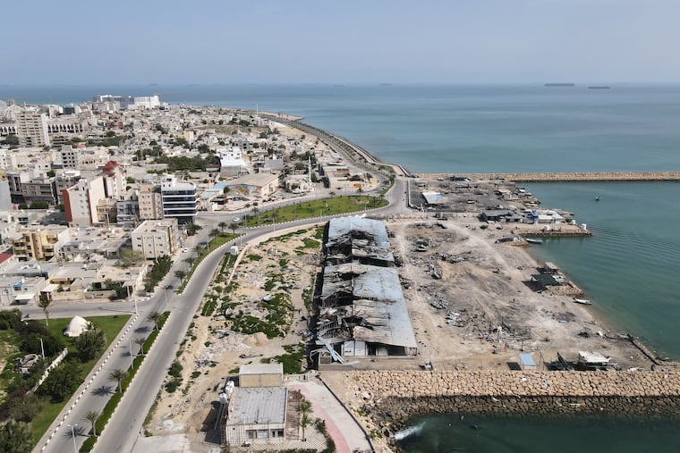 Backdropped by ships in the Strait of Hormuz, damage, according to local witnesses caused by several recent airstrikes during the U.S.-Israel military campaign, is seen on a fishing pier in the port of Qeshm island, Iran, Monday, April 13, 2026.