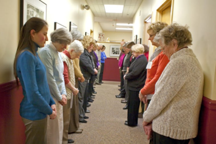 In West Chester, staff members at the Community Volunteers in Medicine facility gather in a hallway for a moment of silence to remember the victims. (Ed Hille / Staff Photographer)