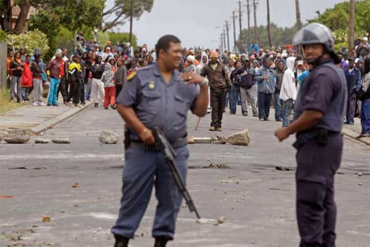 South African policemen provide security as farmworkers demonstrate against low wages in the background by placing rocks in a road in the town of Grabouw. The workers, who are striking during the peak farming season, want their daily wages more than doubled to 150 South African rand ($17.50), saying they can't survive on current salaries. The grape-growing region is key to South Africa's winemaking industry. (S. Van Zuydam / AP)