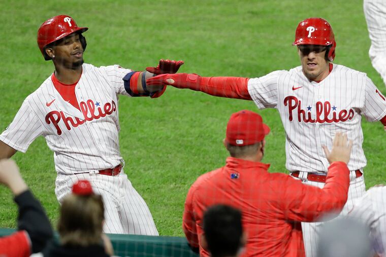 J.T. Realmuto celebrates his run scored with teammate Jean Segura during the Phillies' eighth-inning rally Monday night against the Mets.