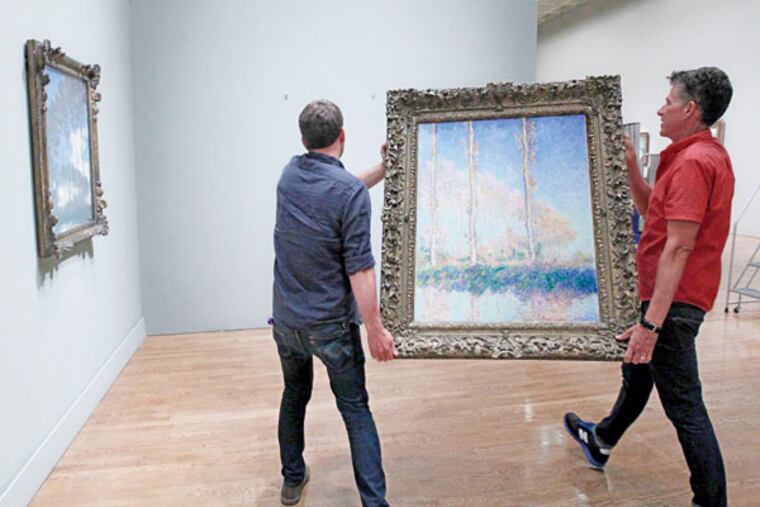 Gus Boyce (left) and Eri Griffin, installers at the Philadelphia Museum of Art, hang Monet’s “Poplars
on the Banks of the River Epte” for the exhibit. (MICHAEL BRYANT/Staff Photographer)