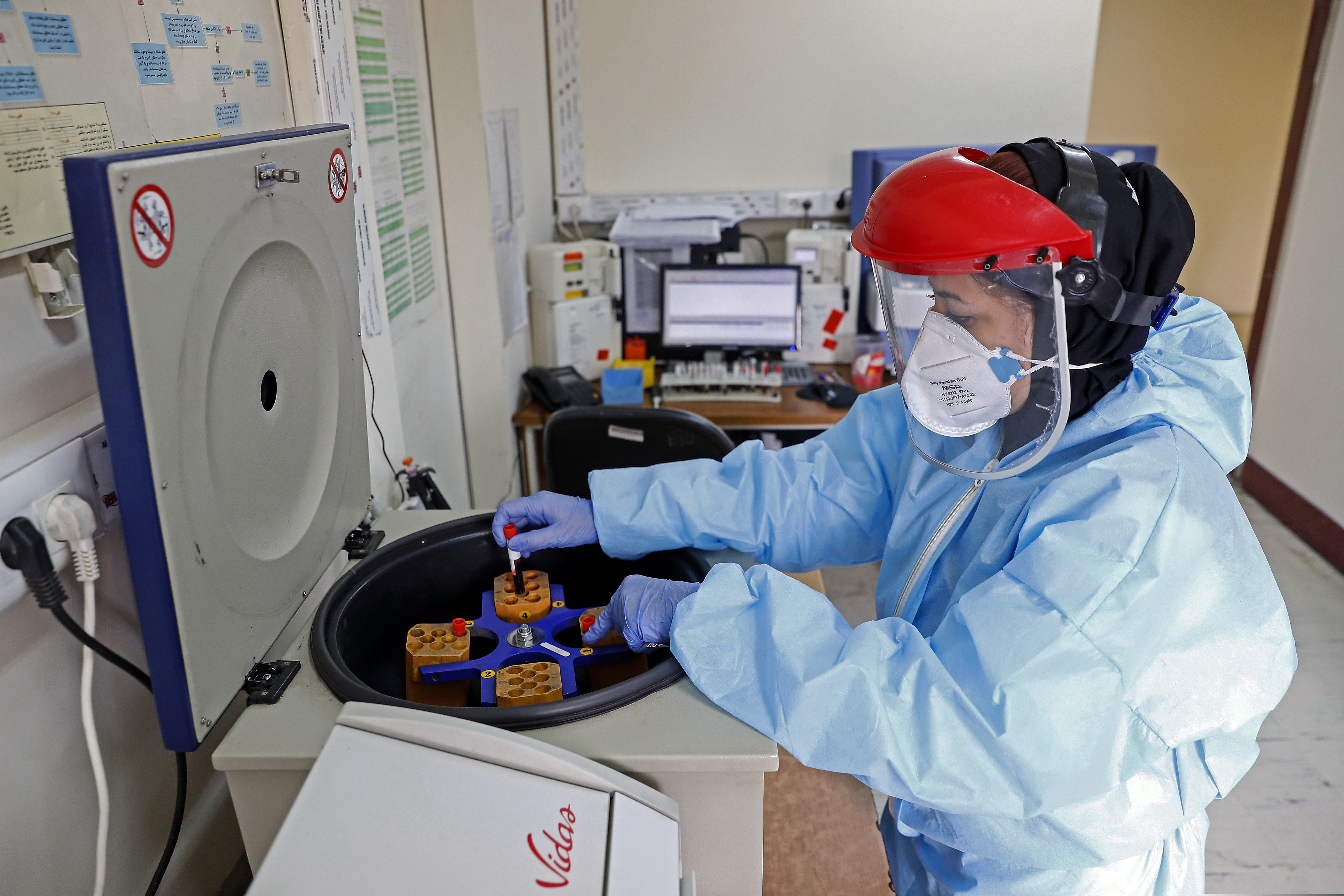 A paramedic works with a centrifuge to test blood samples taken from patients suspected of being infected with the new coronavirus at a hospital in Tehran, Iran. Testing capacity is still limited in the U.S., but ramping up. (Ali Shirband/Mizan News Agency via AP)