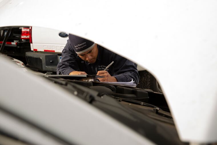 Otoniel "O.T." Figueroa inspects a car at South Philly garage he calls home. Figueroa, 39, started working for the city as a mechanic when he was in high school as part of what's become the city's longest running and most successful apprenticeship program.