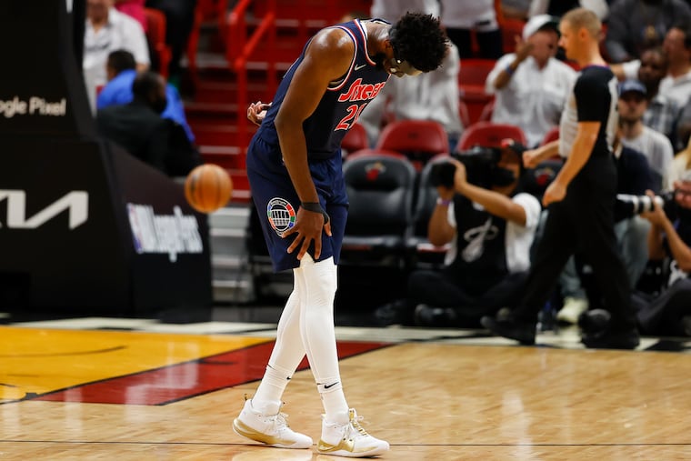 Sixers center Joel Embiid holds his back after trying to save the basketball during the first quarter of Game 5 against the Miami Heat.
