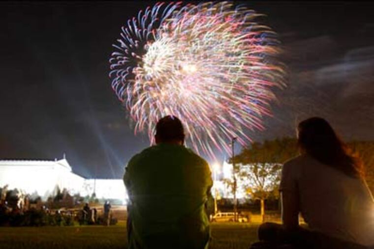 Phil and Denise Riehl watch the fireworks over the Art Museum Sunday night. The night turned violent when an unidentified gunman fired into a crowd walking from Fourth of July celebrations on the Parkway, police said.