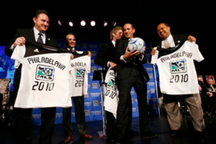 MLS commissioner Don Garber grabs a ball as team owners (from left) Nick Sakiewicz, Robert Buccini, Jay Sugarman and James Nevels hold T-shirts Garber gave them. "We're going to build a team, a stadium, and we're going to lift some trophies along the way," Sakiewicz declared.