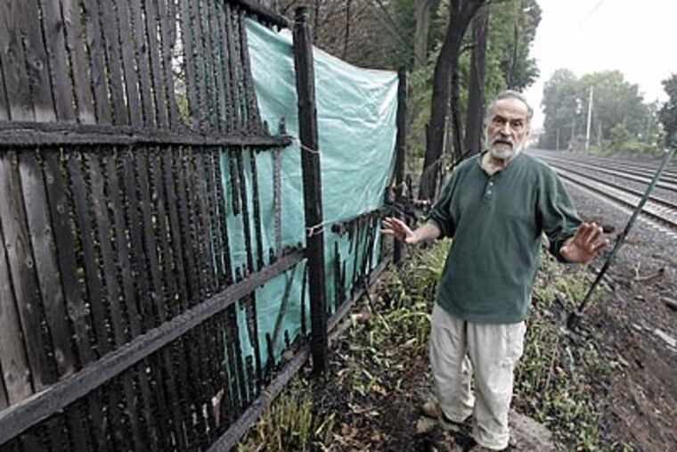 Richard Juliani at his fence in Wynnewood, which was charred by a fire started by a passing locomotive. (Akira Suwa / Staff Photograppher)