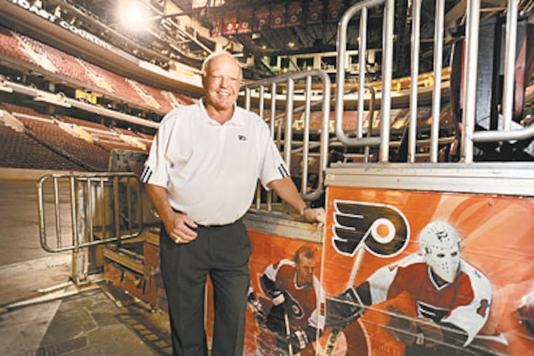 Former Flyer Bob Kelly stands on ice level at the Wells Fargo Center next to photos of himself (closest to his leg) and teammate Bernie Parent during their playing days. (Clem Murray / Staff Photographer)