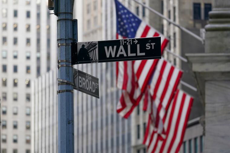 FILE - The Wall St. street sign is framed by the American flags flying outside the New York Stock exchange, Friday, Jan. 14, 2022, in the Financial District. Wall Street is off to a mixed start on Wednesday, May 4, and bond yields are rising as traders mulled an announcement on interest rates from the Federal Reserve. (AP Photo/Mary Altaffer, File)