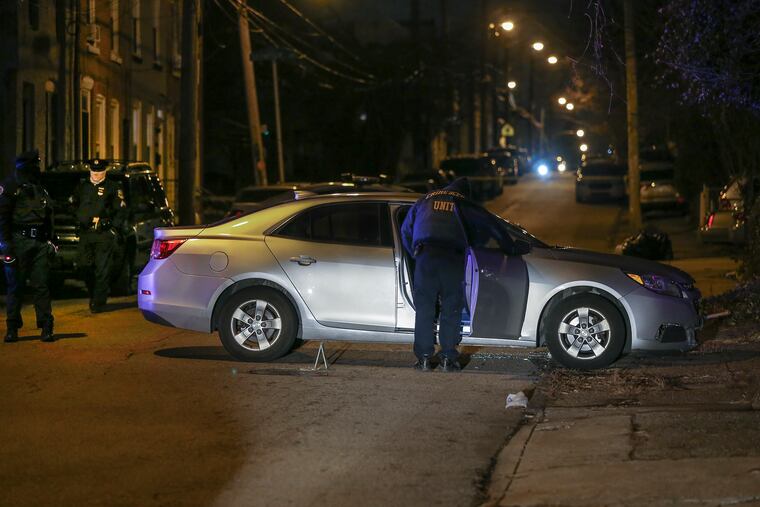 Police inspect a car in the 4900 block of Wakefield Street where a man was fatally shot.