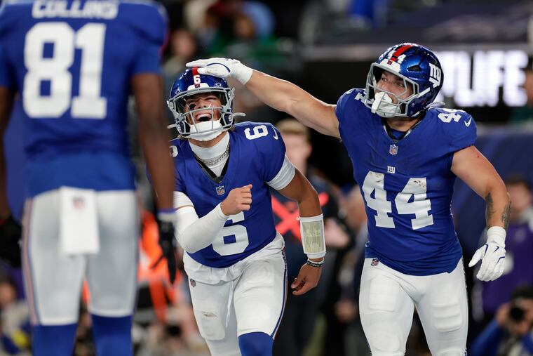 Giants rookies Jaxson Dart, center, and Cam Skattebo celebrate after a touchdown against the Eagles on Oct. 9.