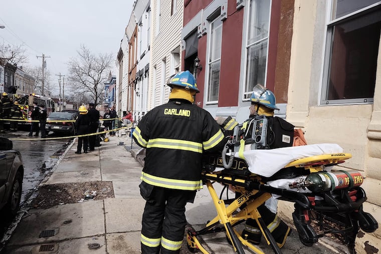 Fire fighters and paramedics at the scene of a fire in the 2400 block of W. Norris St., in North Philadelphia where two firefighters were injured when a ladder came in contact with electric lines on Mar. 16, 2015. (Ed Hille / Staff Photographer )