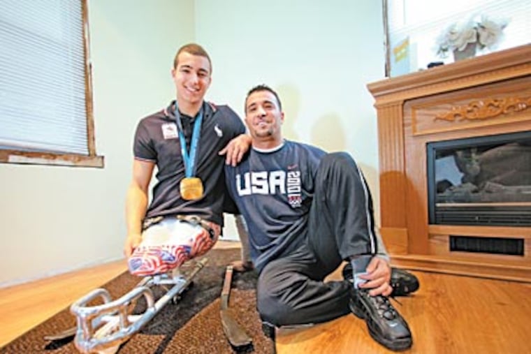 Michael Torres Jr., with his father, Michael Sr., in the double-runner sled in which he helped to win the gold medal for the U.S. sled hockey team in the 2010 Paralympics in Vancouver. He hopes to compete again in 2014. (DAVID M WARREN / Staff Photographer)