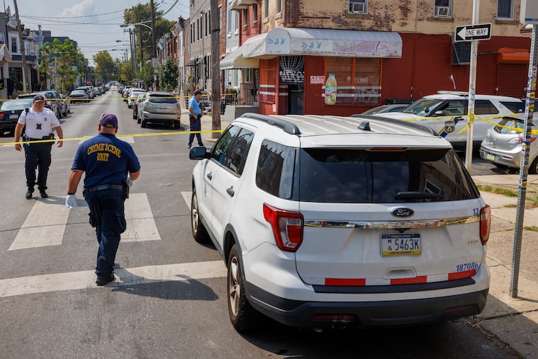 Philadelphia Police Crime Scene officer walks past a city vehicle Thursday morning near where a city worker was shot inside a corner store at 23rd and Oakford Streets Thursday morning during an argument.
