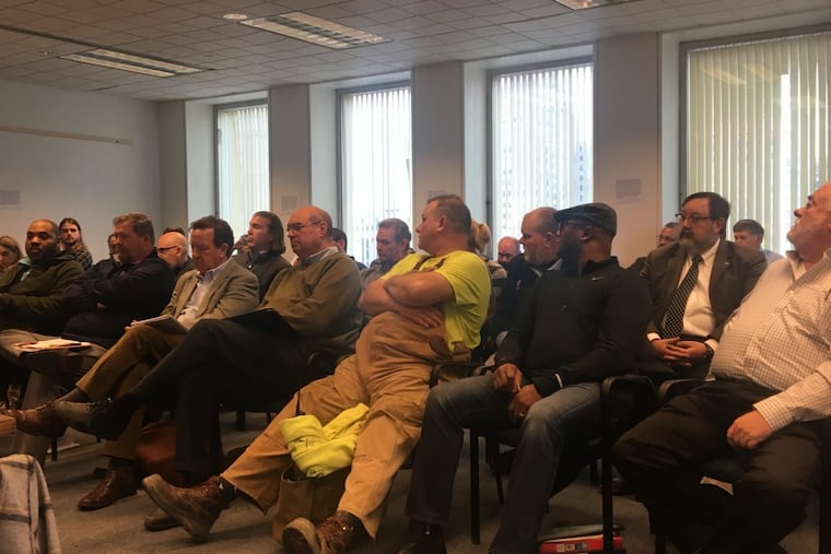 Matt Butterly, a master plumber and president of Big Dawg's Plumbing & Heating, (wearing overalls) listens to a speaker at the first meeting of the revived Plumbing Advisory Board in Philadelphia.