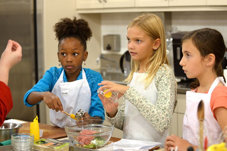 At Sur la Table in the King of Prussia mall, Kennedy Farr (left), Norah Hendrickson, and Anna Welsh pay close attention in cooking class with chef Angie Lee. Kids listen better than adults, Lee says, and often get superior results in class.