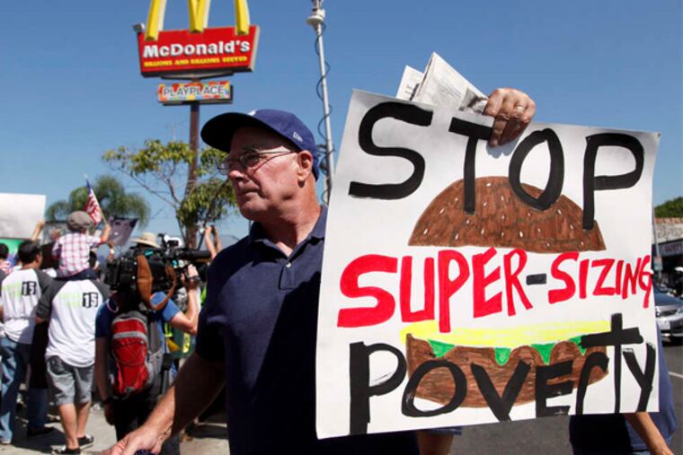 Protesters outside a McDonald's in August in Los Angeles. Protests were held around the country that day, demanding higher wages. A report says families of fast-food workers receive $7 billion a year in public assistance.
