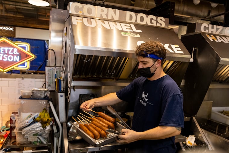 Zach Coleman, Line Cook at Fox & Son, finishes up cooking corndogs for an order at Reading Terminal Market in Center City, Pa., on Wednesday, Aug., 11, 2021. Owner Rebecca Foxman, pays her team around $20/hour and strives to be as transparent and open with her staff as possible.