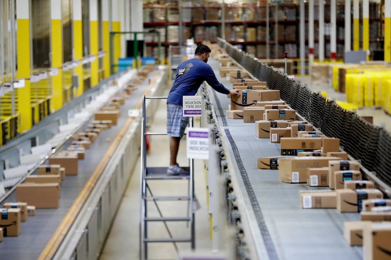 In this Aug. 1, 2017, photo, an Amazon employee makes sure a box riding on a belt is not sticking out at the Amazon Fulfillment center in Robbinsville Township, N.J.