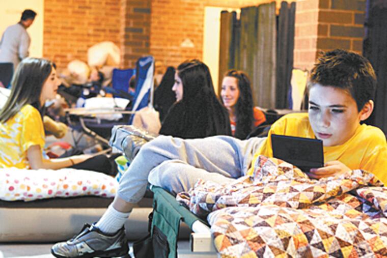 Andy Rears, 10, of Marlton, plays a Nintendo DS game while waiting in line in front of Jazz Unlimited. (Barbara L. Johnston / Inquirer)