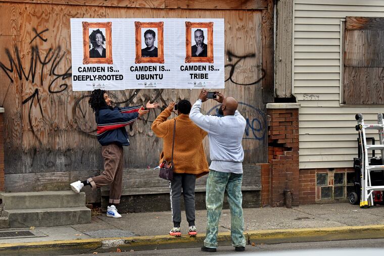 Reet Starwind poses for a photo by Camille Wilson (center) and Erik James Montgomery after he mounted their portraits on an abandoned building on Mount Ephraim Avenue in the Whitman Park neighborhood of Camden. Montgomery has received a grant to photograph 75 Camden residents and pose the question “Camden Is …”
