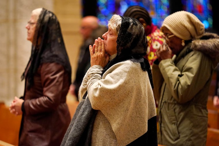 Pam Rousseau, center, and other worshippers pray during a service at the Basilica of Saints Peter and Paul, Sunday in Lewiston, Maine. The community is working to heal following shooting deaths of 18 people at a bowling alley and a bar in Lewiston on Wednesday.
