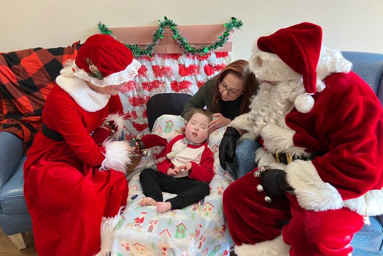 Santa and Mrs. Claus sit with a child and his mother at the Children's Home of Pittsburgh.