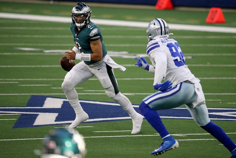 Eagles quarterback Jalen Hurts scrambles away from Cowboys defensive end Dorance Armstrong during the second quarter.