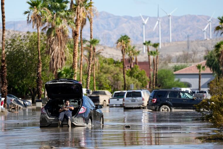 Dorian Padilla sits in his car as he waits for a tow after it got stuck in the mud on a street Monday, Aug. 21, 2023, in Cathedral City, Calif. Forecasters said Tropical Storm Hilary was the first tropical storm to hit Southern California in 84 years, bringing the potential for flash floods, mudslides, isolated tornadoes, high winds and power outages.