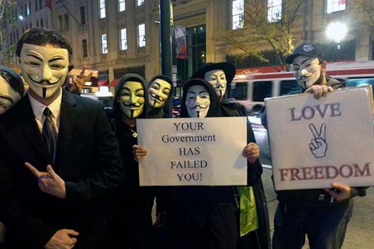 Members of the group Anonymous gather at 8th and Market streets before marching in protest to City Hall Wednesday, November 5, 2014. (Justine McDaniel/staff)