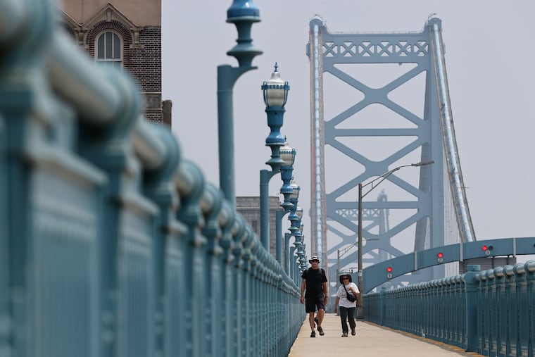 Pedestrians stroll along the Ben Franklin Bridge walkway.