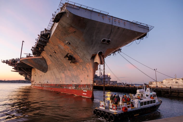 Boat with crew making its way around ship. The decommissioned USS JFK aircraft carrier is being prepared to move from Navy Yard, south Philadelphia, Thursday, Jan. 16, 2025.