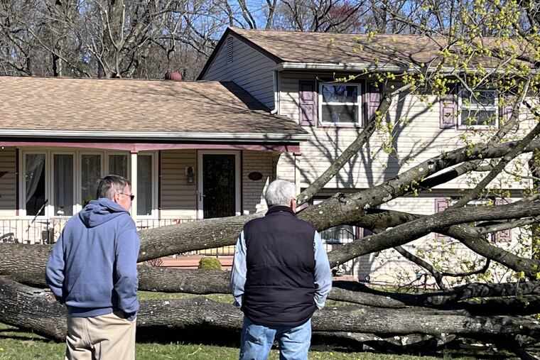 Men survey damage Sunday, April 2, in front of a home on Buttonwood Lane, Cinnaminson, from a suspected tornado that struck April 1, 2023.