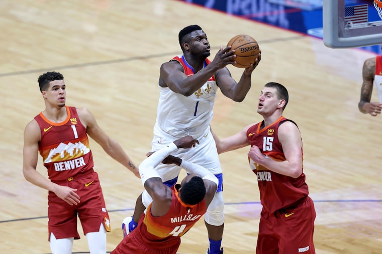 Zion Williamson drives to the basket as Denver Nuggets forward Michael Porter Jr. (1), forward Paul Millsap and center Nikola Jokic (15) defend.