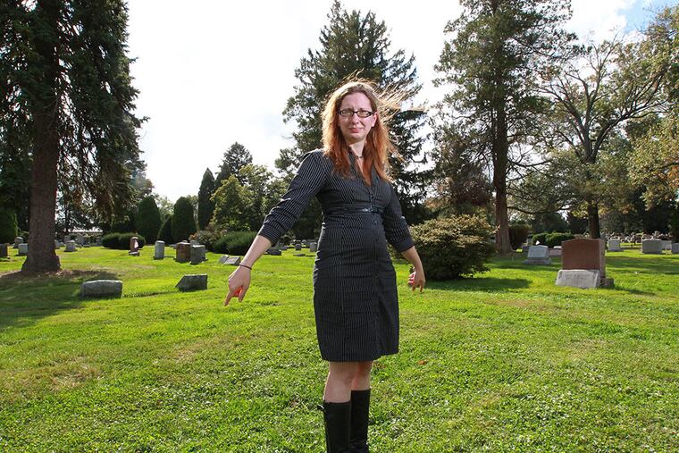 Megan Harris, archivist at Arlington, stands over the ground where the bodies of over 120 immigrants from Lazaretto Quaratine Station in Tinicum are buried at Arlington Cemetery. There is no marker. ( MICHAEL BRYANT / Staff Photographer )