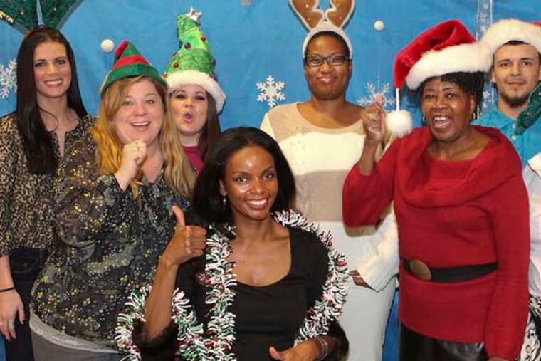 DN's Jenice Armstrong, center, with 9 of the 10 recipients of Daily News' third-annual, Oprah-style Holiday Gift Giveaway, Thursday, December 20, 2012. ( STEVEN M. FALK/ Staff Photographer )