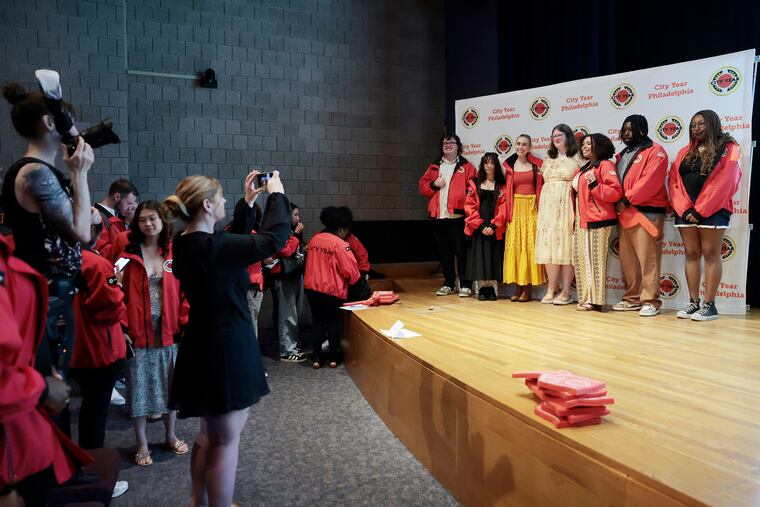 City Year student success coaches pose for group photos at their graduation ceremony inside the Academy of Natural Sciences in Philadelphia on Friday. The AmeriCorp programs graduated 77 volunteers after a funding cut instituted by the Department of Government Efficiency.