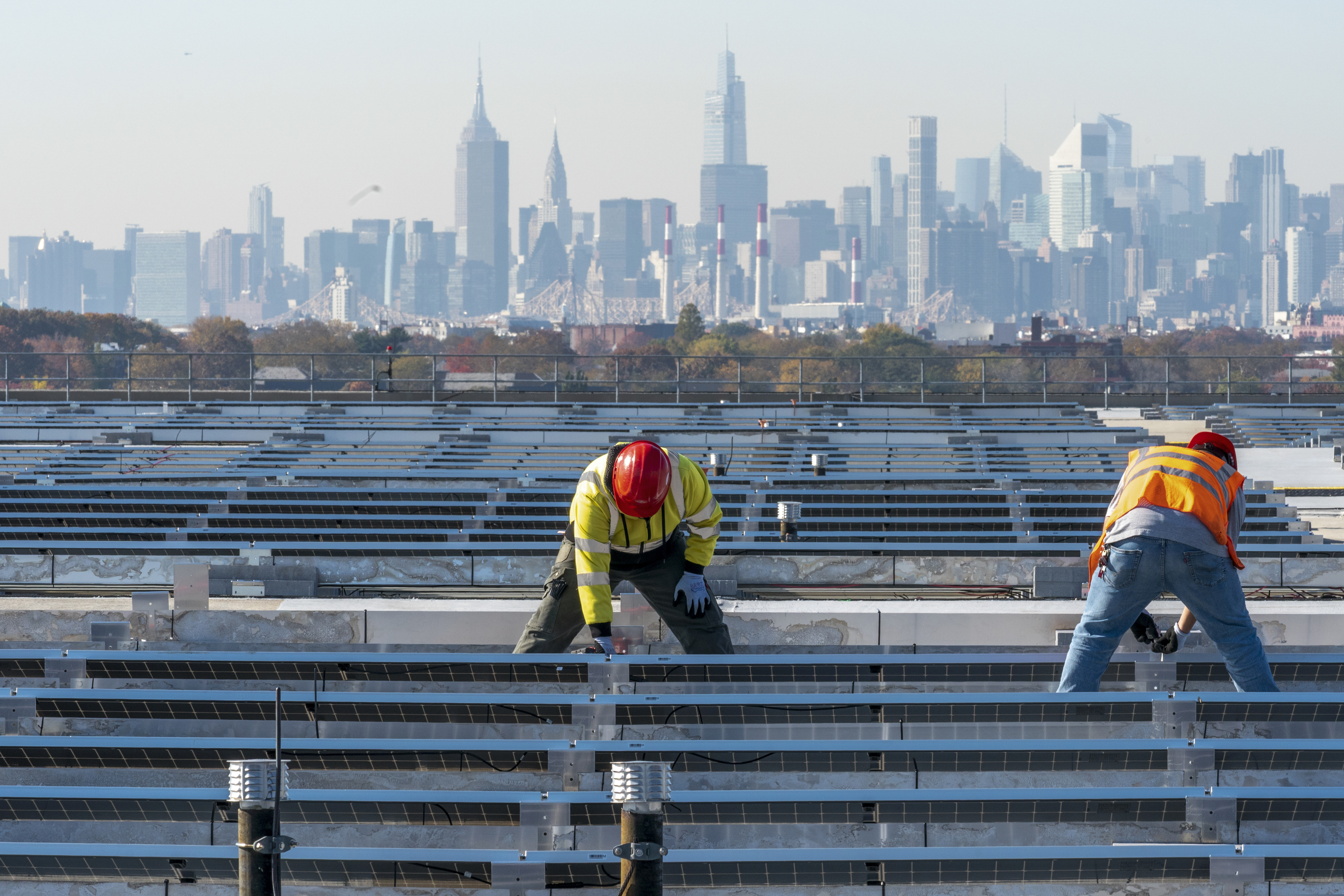 Framed by the Manhattan skyline electricians with IBEW Local 3 install solar panels on top of the Terminal B garage at LaGuardia Airport, Tuesday, Nov. 9, 2021, in the Queens borough of New York. As climate change pushes states in the U.S. to dramatically cut their use of fossil fuels, many are coming to the conclusion that solar, wind and other renewable power sources won't be enough to keep the lights on. Nuclear power is emerging as an answer to fill the gap as states transition away from coal, oil and natural gas to reduce greenhouse gas emissions and stave off the worst effects of a warming planet.