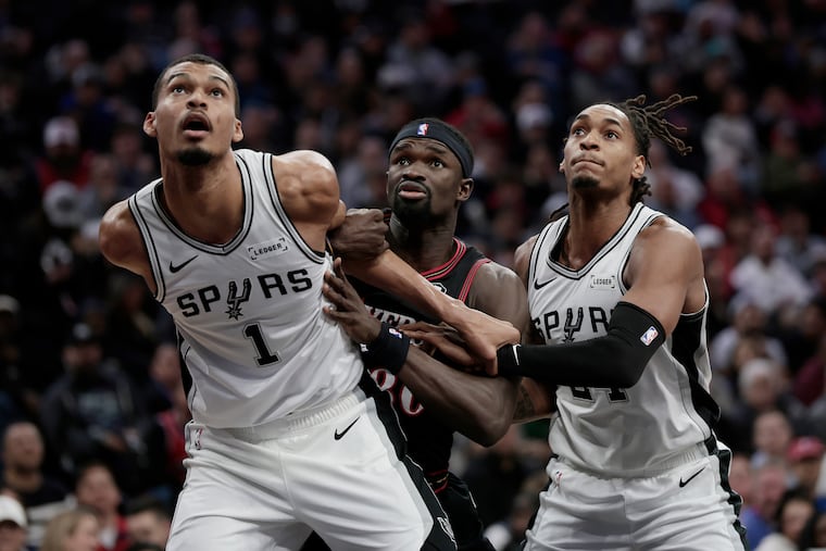 The Spurs' Victor Wembanyama and Devin Vassell (right) block out the Sixers' Adem Bona.