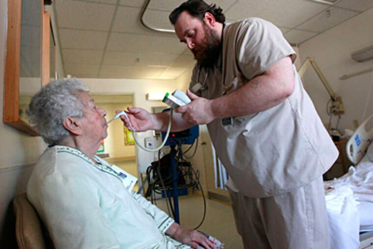Hahnemann registered nurse Daniel Lewis takes the temperature of patient Jenne Tatulli of Burlington. (David Swanson/Staff)